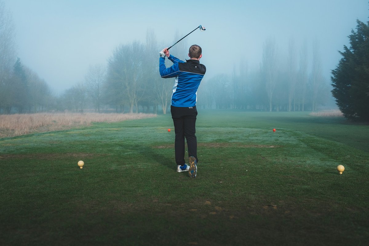 Golfeur au départ d'un trou, un matin de brume